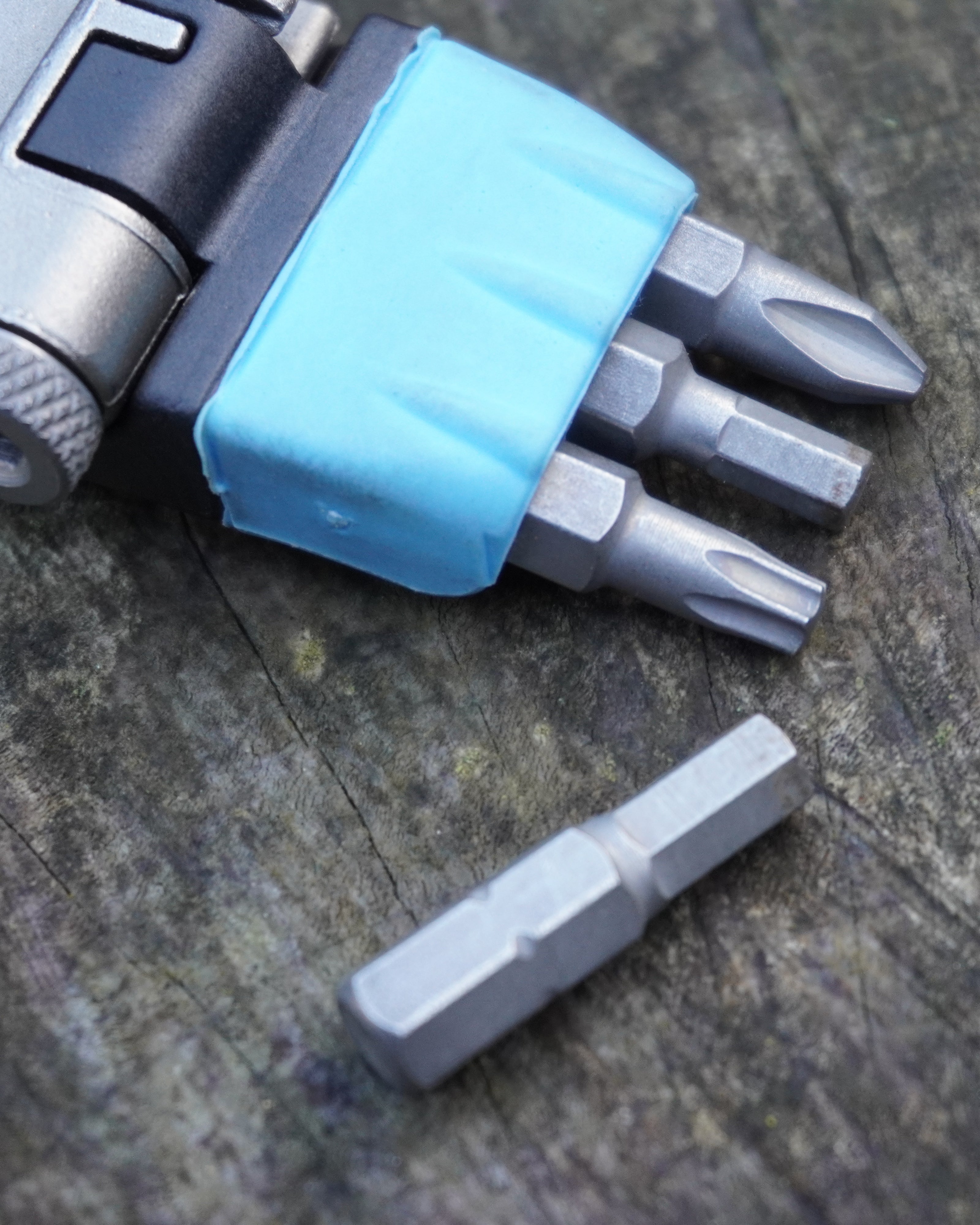 Close-up of ML125 multi tool showing stored tool bits in blue holder with one bit removed and placed on surface