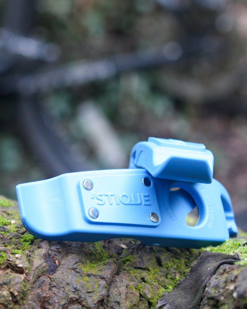 Close-up of ML14 blue bike tyre lever resting on a mossy log in woodland setting