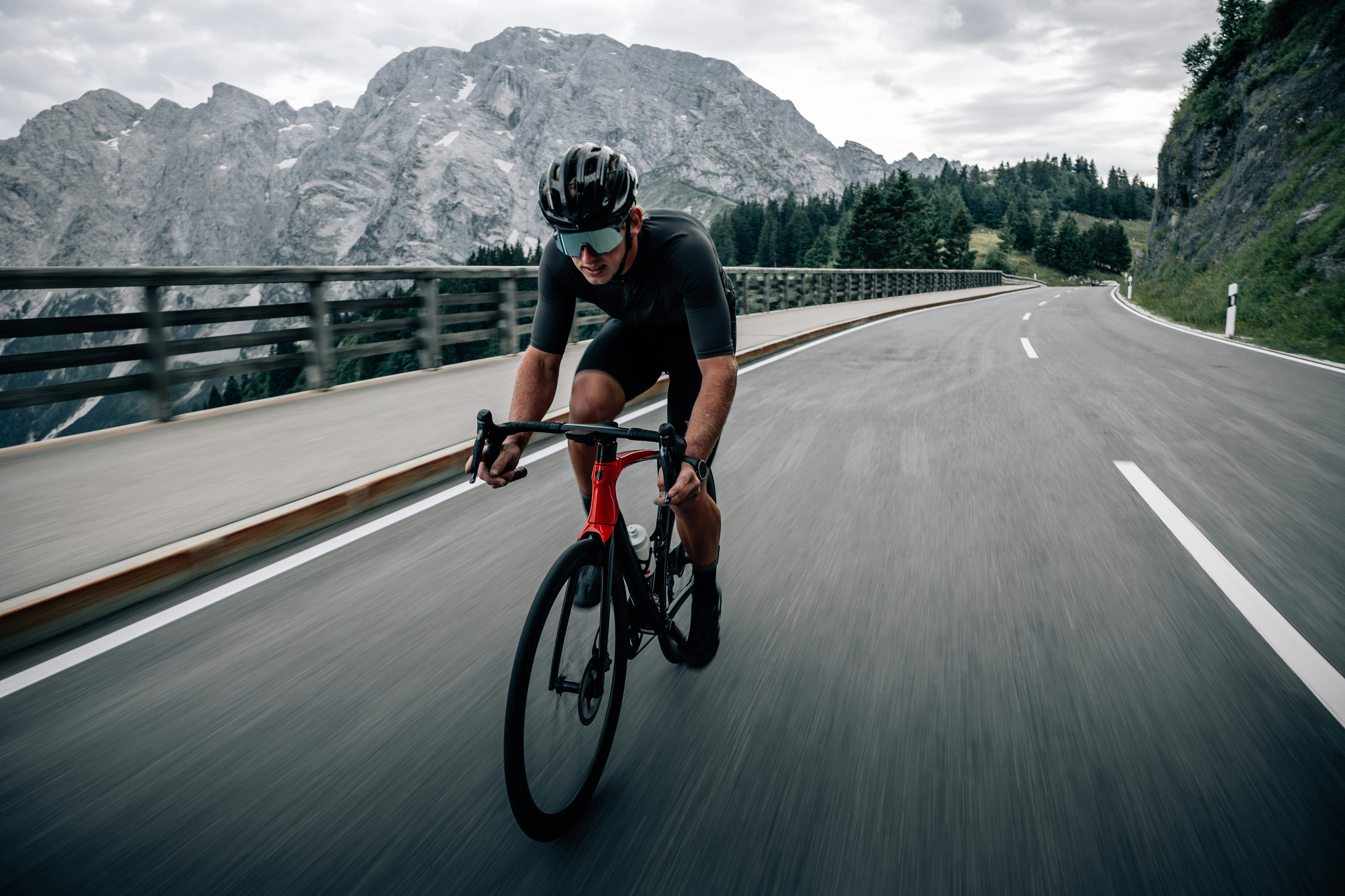 Cyclist riding on mountain road wearing helmet and sunglasses – Stique bike tools banner image